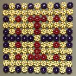 A square grid arrangement of octagonal faucet handles, creating an 11x11 pattern. The handles are in three colors: yellow (predominant), purple (along the edges and in specific patterns), and red (forming a cross or plus sign in the center). Each handle has a spoked wheel design and a central metal bolt. The handles appear to be made of plastic or painted metal and are photographed against a neutral grey background. The arrangement creates a symmetrical, decorative pattern reminiscent of pixel art or a quilt design. by James K-M